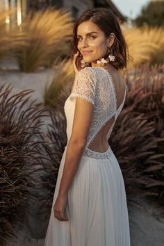 a woman in a white dress is posing for the camera with her back to the camera