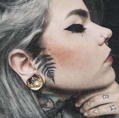 a woman with tattoos and piercings on her face