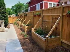 a row of wooden planters sitting on top of a sidewalk next to a fence