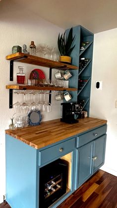 a kitchen with blue cabinets and shelves filled with wine glasses