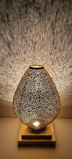 a black and white vase sitting on top of a wooden stand under a light fixture