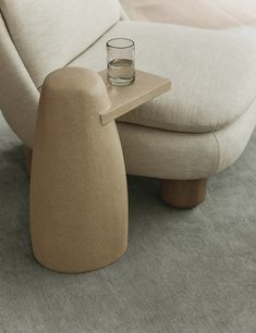 a small glass sitting on top of a table next to a chair and footstool