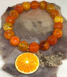 This gorgeous orange 🍊 stretch bracelet is made with stunningly gorgeous 10 mm orange faceted agate beads & is finished off with a realistic looking orange 🍊slice gold plated enamel charm.  It's so bright and beautiful and perfect for the summer🍊☀️🍊☀️.  7 inches in length on 100% polyester stretch cord, not wire. BEADS WILL VARY FROM THE PIC, as this is a made to order bracelet. Handmade Orange Agate Bracelets, Handmade Orange Agate Bracelet, Adjustable Orange Agate Bracelet, Adjustable Orange Agate Bracelets, Handmade Spiritual Orange Stretch Bracelet, Handmade Orange Agate Beaded Bracelets, Orange Round Carnelian Beaded Bracelets, Orange Beaded Bracelets For Gift, Orange Carnelian Round Beaded Bracelets