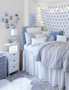 a white and blue bedroom with lots of pillows on the headboard, bedding and nightstands