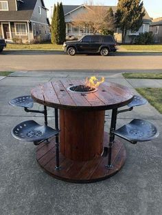 an outdoor table made out of metal and wood with fire pit in the middle on top