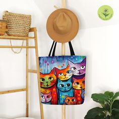 a bag with cats on it hanging from a wall next to a hat rack and potted plant