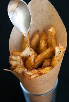 the french fries are being served with a spoon