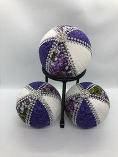 three purple and white balls on a black stand