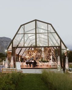 an outdoor wedding venue with a piano in the center and string lights hanging from the ceiling