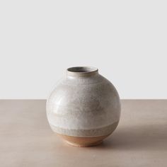 a white vase sitting on top of a wooden table