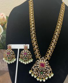 Enhance your beauty with this radiant gold-plated necklace, featuring a delicate design adorned with stunning ruby, green and white cubic zirconia (CZ) stones. Complemented by matching earrings, this set exudes elegance and grace, making it perfect for any special occasion. Features: *Design: Elegant gold-plated necklace with intricate detailing *Stones: Adorned with high-quality green and white CZ stones for a dazzling effect *Earrings: Matching earrings included to complete the set *Materials: Elegant Multi-stone Gold Jewelry Sets, Elegant Gold Multi-stone Jewelry Sets, Gold Gemstone Necklace With Cubic Zirconia, Cubic Zirconia Kundan Necklace With Intricate Design As Gift, Kundan Necklace With Cubic Zirconia As A Gift, Elegant Gold Multi-stone Kundan Necklace, Dazzling Hand Set Gold Emerald Necklace, Green Ruby Jewelry With Intricate Design, Dazzling Gold Emerald Necklace For Wedding