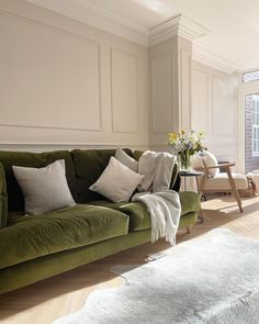 a living room filled with green couches and white walls in front of a window