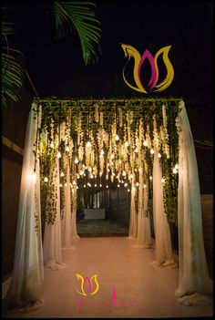 an outdoor wedding arch decorated with lights and greenery