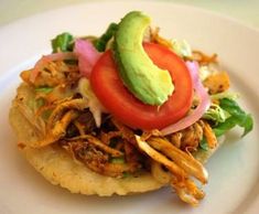 a white plate topped with a taco covered in meat and veggies