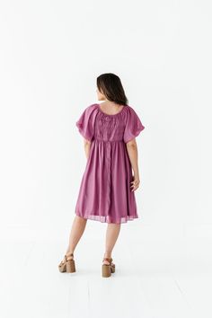 Features Round neckline Short puff sleeve with elastic cuff Elastic waist Smocked back Fully lined Pockets Deep orchid color with shimmer overlay Dress & Lining: 100% Polyester Size + Fit XS 00-2, Small 2-6, Medium 8-10, Large 12-14, X-Large 14-16, 2X 20-22, 3X 24-26, 4X 28-30 Kristin is 5'4", a size 1 and is wearing a Small Jaycie is 5'6", a size 18 and is wearing a 2X Runs true to size. Bust Measurements taken while laying flat and then doubled. They do no account for stretch. Click here for s Flowy Smocked Dress With Flutter Sleeves, Flowy Smock Midi Dress For Daywear, Modest Smocked Summer Dress For Daywear, Flowy Smocked Dress With Gathered Neckline For Daywear, Flowy Smocked Dress With Short Sleeves, Daywear Smocked Flutter Sleeve Dress With Ruched Detail, Modest Flowy Smocked Dress For Summer, Daywear Flutter Sleeve Midi Dress With Smocked Bodice, Modest Smocked Short Sleeve Dress