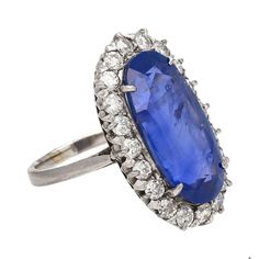 Shop this antique relic from a simpler time. An unheated 11.30-carat oval cut Blue Sapphire of Burmese origin. Set in platinum with a round-cut diamond halo. GRS certified with origin report. Circa late 1800's. The sapphire's natural inclusions, akin to distinctive birthmarks, give the stone a genuine authenticity and individuality, adding a unique personality and character.  This ring features a long oval cut that sits beautifully on the finger. Designed with an open back setting that maximizes Antique Blue Oval Diamond Ring, Victorian Sapphire Ring With Diamond Oval Shape, Antique Oval Sapphire Diamond Ring, Victorian Oval Sapphire Ring With Diamond, Vintage Blue Sapphire Oval Cabochon Ring, Antique Oval Sapphire Ring In Platinum, Pink Pear Diamond Ring, Wide Band Engagement Ring, Light Refraction