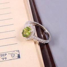 a ring sitting on top of an open book with a green stone in the middle