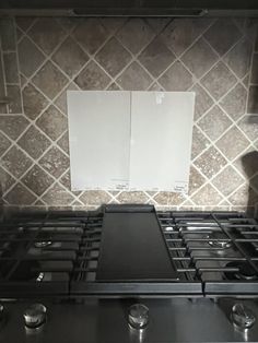 a black stove top oven sitting next to a white tile backsplash in a kitchen