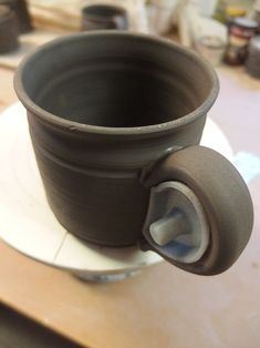 a black cup sitting on top of a white plate