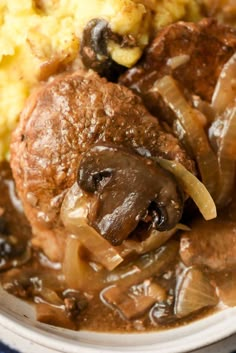 a close up of a plate of food with meat and mushrooms on it, next to mashed potatoes