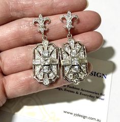 "A pair of Art Deco wedding bridal earrings with Victorian fleur de lis sterling silver posts and Gatsby 1920s vintage style inspired geometric dangles. These elegant lightweight earrings are made of sparkly clear cubic zirconia with posts. Earrings are about 1 5/8\" (4.2cm) with posts. View matching pieces and similar designs at https://etsy.me/2Mu6wjC and https://etsy.me/2FqTa3I Matching brooch pin at https://etsy.me/2Wk6HzE See all geometric designs at https://etsy.me/2eKf6s8 View all earring Gatsby Earrings, Regency Wedding, 1920s Vintage, Deco Wedding, Earrings Geometric, Back Jewelry, Wedding Jewelry Earrings, Zirconia Earrings, Lightweight Earrings