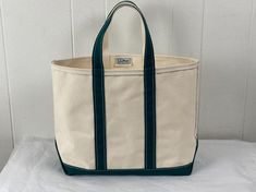 Vintage 1980s(?)  thick natural canvas bag with dark green trim and bottom. L.L. Bean Boat and Tote. Has two handles and one main compartment. Label reads: Made by L. L. Bean Freeport Maine Boat and Tote.  Bag measures  15" wide,  12" tall  6" thick Handles hang down 6" In excellent condition, it looks unused. Vintage Cotton Canvas Bag With Large Capacity, Vintage Canvas Tote Bag For School, Green Canvas Bag With Canvas Lining For Travel, Vintage Green Bags For Errands, Vintage Canvas Bag With Large Capacity, Vintage Canvas Bag With Large Capacity For School, Vintage Green Canvas Bag For Travel, Vintage Style Large Capacity Canvas Bag, Canvas Bucket Bag For Errands