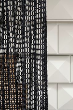 a close up of a black curtain in front of a wall with white and brown tiles