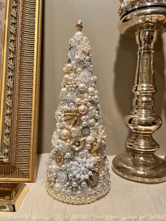 a small christmas tree sitting on top of a table next to a gold framed mirror