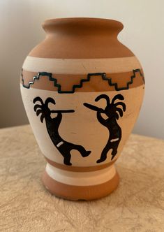 a brown and white vase sitting on top of a table