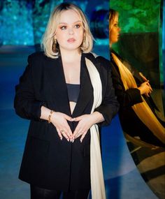 a woman standing in front of a painting with her hands on her hips and looking at the camera