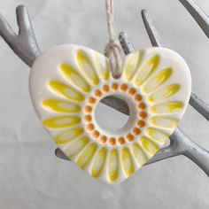 a ceramic heart ornament hanging from a metal hook with antlers around it