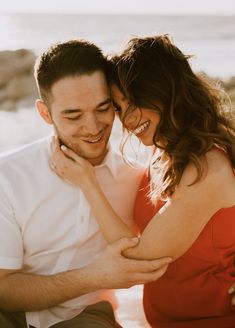 a man and woman sitting next to each other on the beach smiling at each other