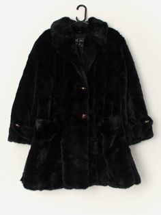 Vintage faux fur long coat in black. This stunning coat from the 1980s is in a stunning glossy black and features two large front hand pockets, stunning black and gold buttons, a soft lining in black and split hems. A lovely jacket that will keep you nice and snug in the colder months! Made from a soft, heavyweight material. Made in Italy.  Our recommended size: Medium to large  Label says: No size label Condition: Very good Material: No care label  Measurements in inches: Pit to pit: 23 Shoulders: 18 Front length: 34.5 Back length: 35 Sleeve length: 23.5 Hem unstretched: 26  We recommend that you compare our measurements to a similar item of your own to ensure good fit. Measurements are taken flat and doubled for waist and hip. Our items are vintage and may show signs of previous wear, et Evening Outerwear With Faux Fur Lining In Mink Color, Black Long Faux Fur Coat, Black Faux Fur Evening Coat, Black Faux Fur Coat For Evening, Evening Black Faux Fur Coat, Black Fur Coat With Faux Fur Trim For Party, Black Fur Coat With Faux Fur Lining For Party, Black Faux Fur Outerwear For Evening, Black Formal Fur Coat With Faux Fur Trim