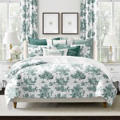 a bedroom with green and white bedding in front of two windows, framed pictures on the wall