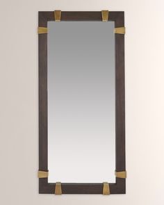 a mirror that is on the wall with some gold tape around it and two handles