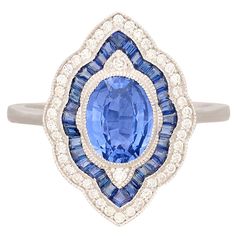 a blue and white diamond ring with an oval shaped center surrounded by smaller round diamonds