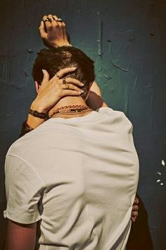 two people standing next to each other with their hands on the back of their heads