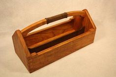 an empty wooden box with a handle on the top and bottom, sitting on a white surface