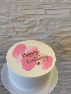 a white cake with pink frosting and two hearts on the top that says happy birthday