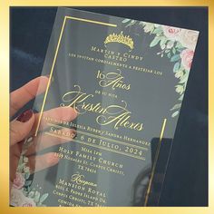 a person holding up a wedding card with flowers on the front and back cover in gold foil