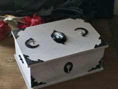 two pairs of earrings sitting in a box on a table next to some red flowers