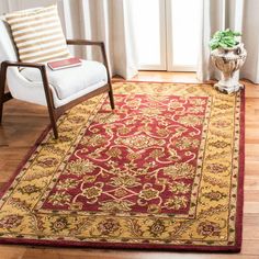 a living room with a chair and rug on the floor next to a large window