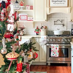 a christmas tree is in the middle of a kitchen decorated with red, white and green ornaments