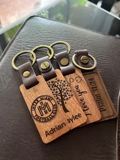 four wooden keychains sitting on top of a leather table next to each other