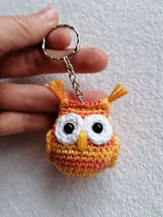 a small crocheted owl keychain is being held by someone's hand