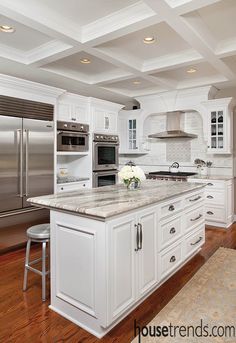 a large kitchen with white cabinets and stainless steel appliances, along with hardwood flooring