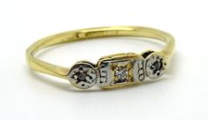 a gold and diamond ring with three stones on the side, sitting on a white surface