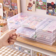 a person holding a plastic container filled with lots of stickers on top of a table