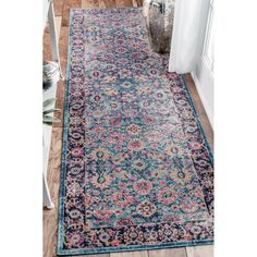 a blue and pink area rug with an ornate design on the bottom, in front of a