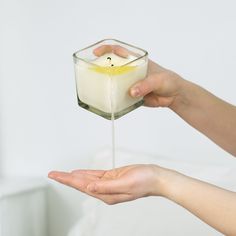 a person holding a candle in their hand with liquid pouring from the top into it